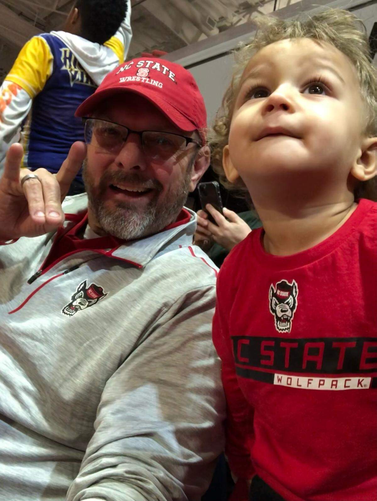 N.C. State alumnus and athletics supporter Chuck Coates, then-56, takes a photo with his grandson Traylan Thorpe, then-2 years old, at a wrestling match in 2023. 