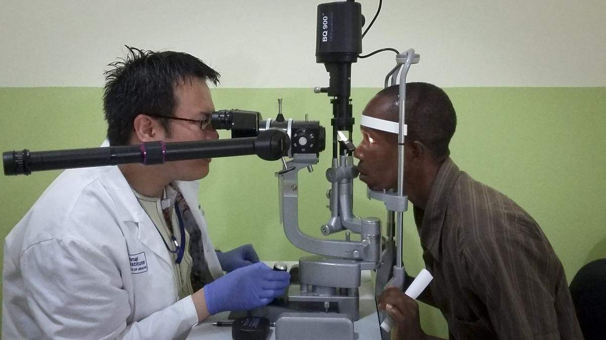 In this photo taken Friday, July 31, 2015, Dr. Zan Yeong, left, an eye specialist for a joint Liberian-American Ebola initiative known as the Partnership for Research on Ebola Vaccine in Liberia (PREVAIL), examines the eyes of Ebola survivor Abraham Moses, who has problems with his vision, at the John F. Kennedy Medical Center in Monrovia, Liberia.