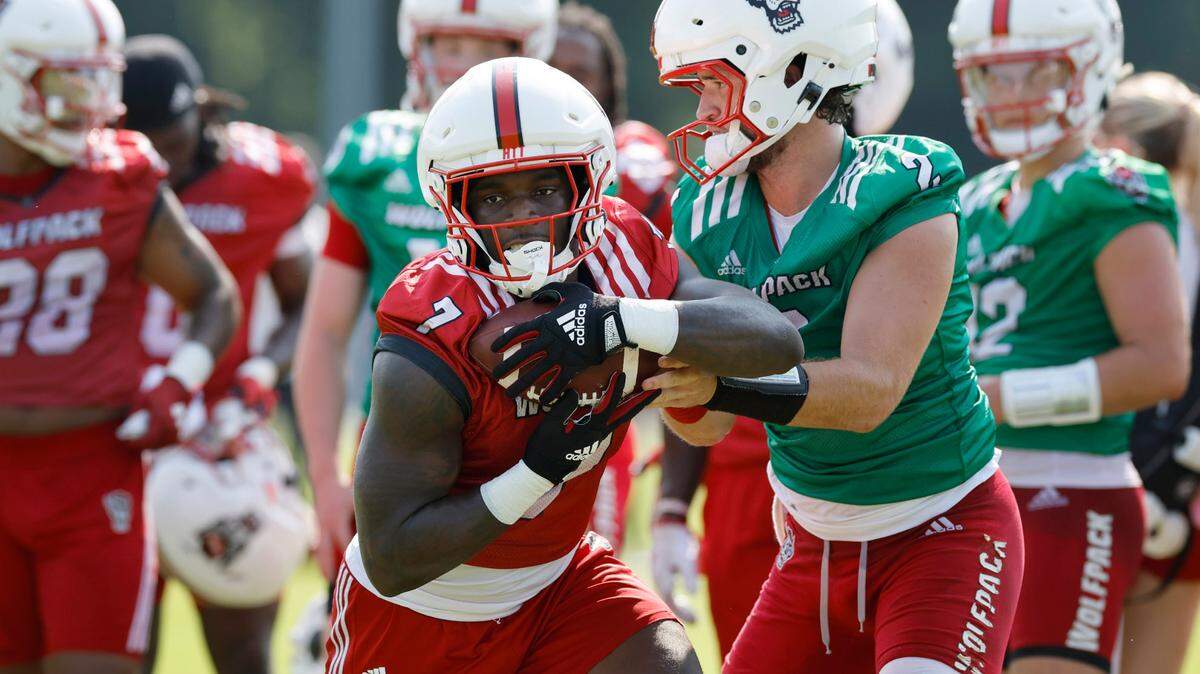 N.C. State running back Jordan Waters (7) takes the handoff from quarterback Grayson McCall (2) during the Wolfpack’s first practice in Raleigh, N.C., Wednesday, July 31, 2024.