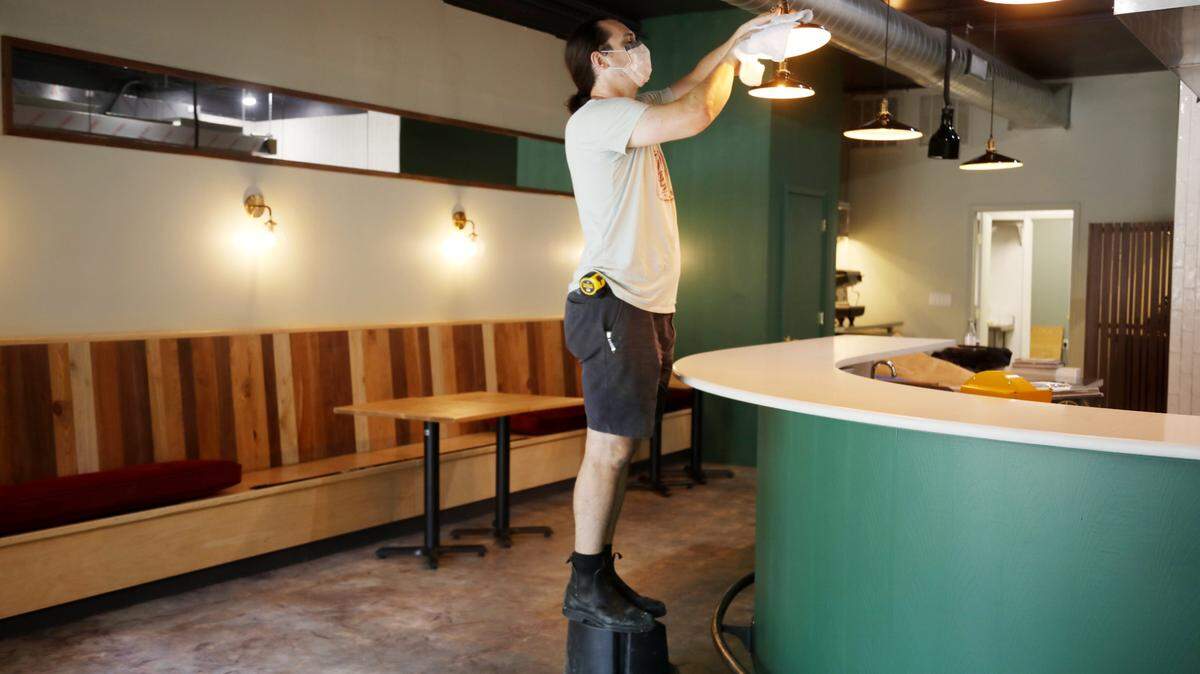 Owner David Peretin cleans the lights at Tesoro in Carrboro on Monday, Aug. 2, 2021. Peretin hopes to open the new Italian restaurant soon.