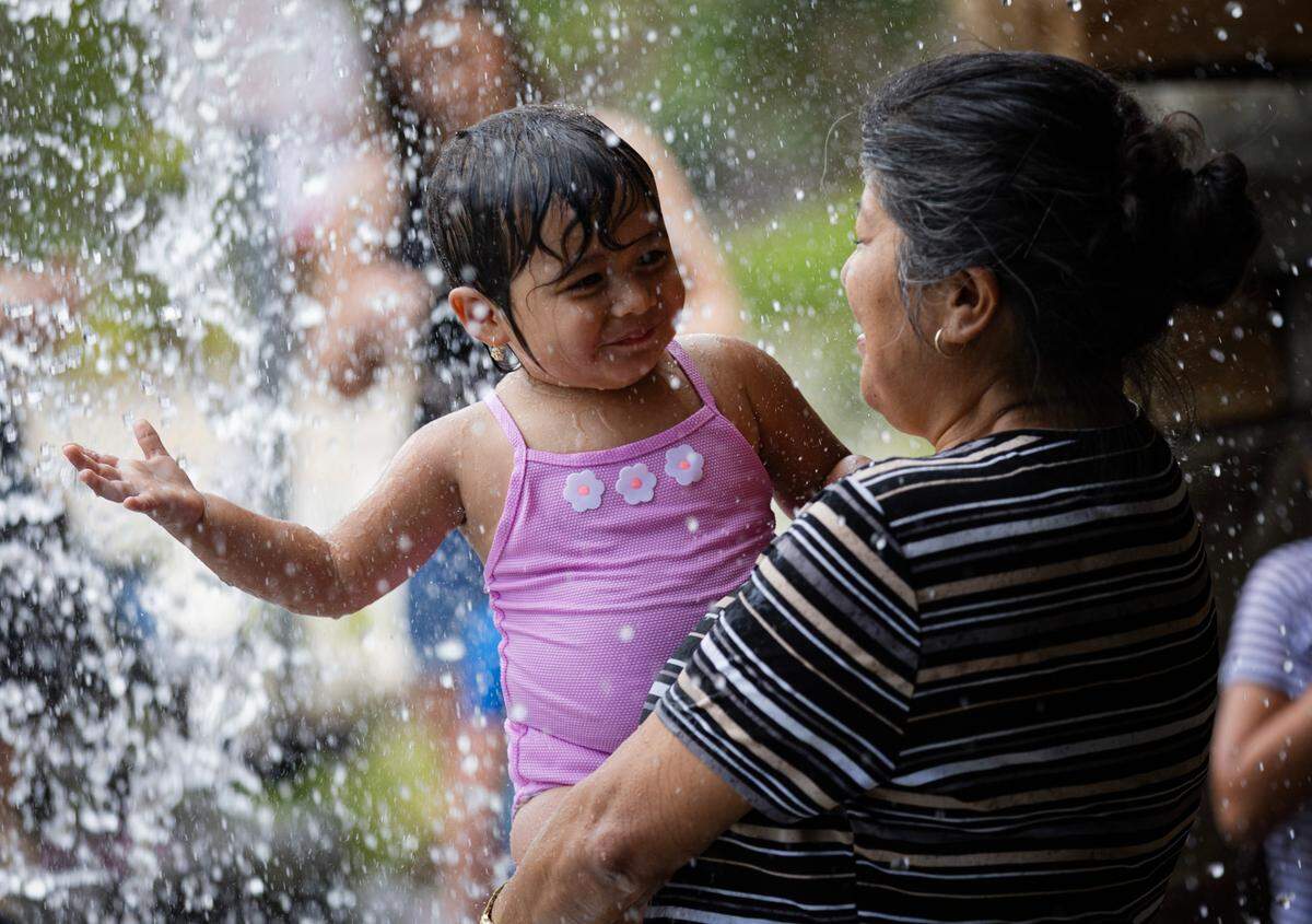 Magdalena Cruz-Vazquez plays with her granddaughter Lali under the waterfall at Gipson Play Plaza in Raleigh, N.C. on Thursday, July 3, 2025.