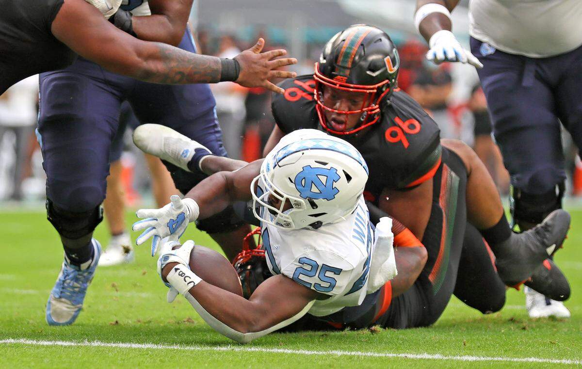 Miami Hurricanes defensive lineman Jonathan Ford (96) fails to stop North Carolina Tar Heels running back Javonte Williams (25) as he scores a first quarter touchdown at Hard Rock Stadium In Miami Gardens, Florida, Saturday, December 12, 2020.