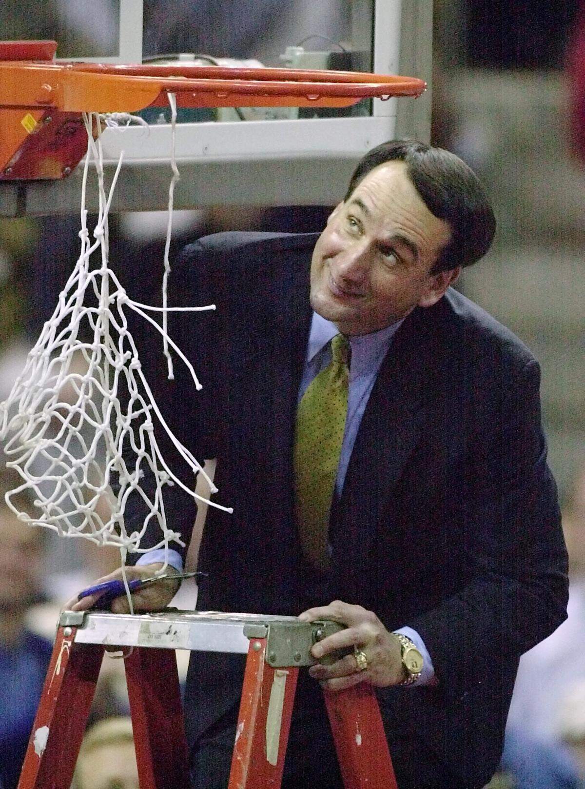 Duke head coach Mike Krzyzewski smiles at the rim after bumping his head as he prepared to cut down the net after the Blue Devils defeated Maryland in the 2000 ACC Tournament Championship game 81-68. 