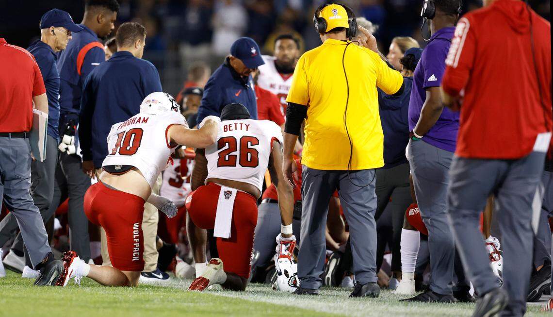 N.C. State’s Caden Fordham (10) and Devon Betty (26) watch as medical personnel attend to Rakeim Ashford during the second half of N.C. State’s 24-14 victory over UConn at Rentschler Field in East Hartford, Conn. Thursday, August 31, 2023. Ashford was taken off the field on a stretcher after being injured on a kickoff return.