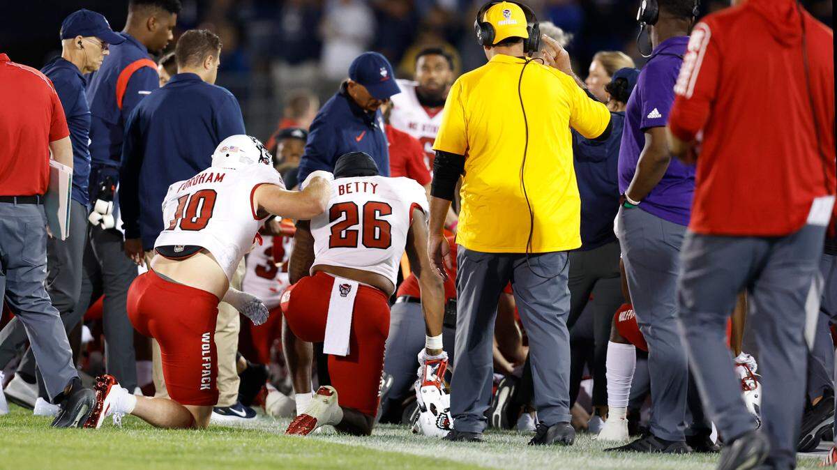 N.C. State’s Caden Fordham (10) and Devon Betty (26) watch as medical personnel attend to Rakeim Ashford during the second half of N.C. State’s 24-14 victory over UConn at Rentschler Field in East Hartford, Conn. Thursday, August 31, 2023. Ashford was taken off the field on a stretcher after being injured on a kickoff return.