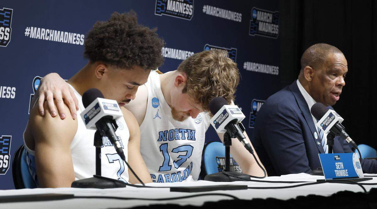 North Carolina's Henri Veesaar (13) puts his arm around Seth Trimble (7) as head coach Hubert Davis speaks during a press conference after VCU’s 82-78 overtime victory over UNC in the first round of the NCAA Men’s Basketball Tournament at  Bon Secours Wellness Arena in Greenville, S.C., Thursday, March 19, 2026.