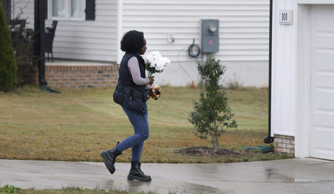 Deondra Crudup brought stuffed animals and flower to place on the porch of the home of Wellington Dickens III in Zebulon, N.C., Wednesday, Oct. 29, 2025. Dickens faces four charges of murder in the deaths of his children 6-year-old Leah Dickens, 9-year-old Zoe Dickens, 10-year-old Wellington Dickens IV and 18-year-old Sean Brasfield, his stepson.