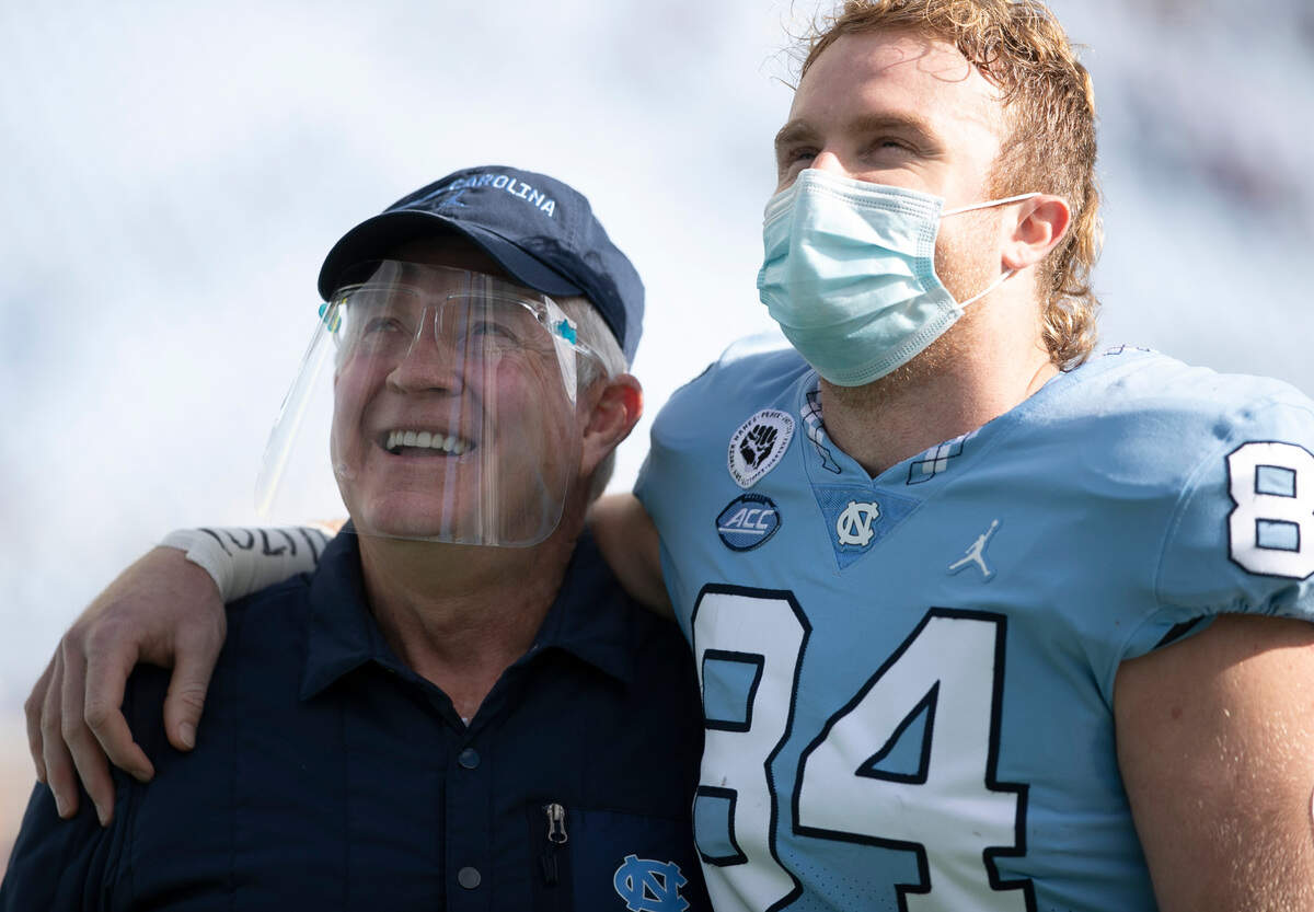 Senior Garrett Walston (84) embraces North Carolina coach Mack Brown as 16 Tar Heel seniors are recognized before playing their final home game in Kenan Stadium on Saturday, December 5, 2020 in Chapel Hill, N.C.