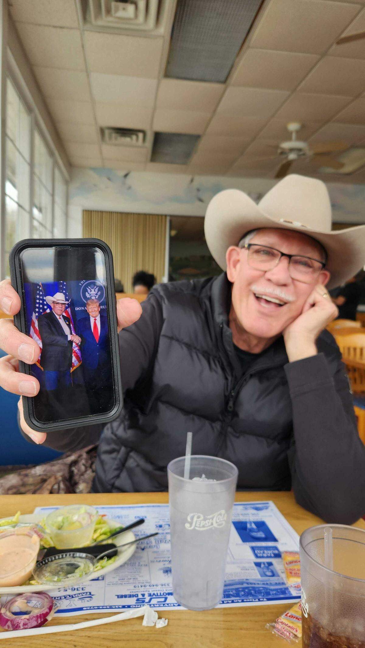 Rockingham County Sheriff Sam Page shows a photo of himself and President Donald Trump during an interview with The News & Observer a week before the 2026 primary election.