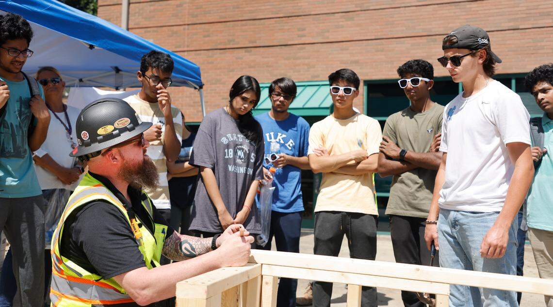Students from Green Level High School watch as Bobbitt’s Paul Murray demonstrates how to toenail wood during Construction Field Day at Bobbitt Design Build in Raleigh, N.C., Tuesday, July 19, 2022. Around 100 Wake County high school students visited Bobbitt to see the kinds of high-paying jobs that are available in the construction industry. It’s part of the WakeEd Partnership’s Career Accelerator Program that’s giving 400 students a chance to learn more about jobs in different fields such as construction, the hospitality industry, health care and information technology.