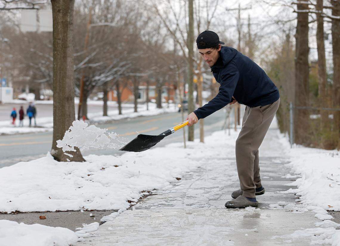 Taylor Wells works to shovel snow and ice from a sidewalk along Club Boulevard on Thursday, Feb. 20, 2025, in Durham, N.C.