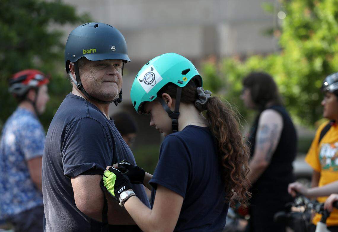 Lillie Martin, 13, helps her father, Carl Martin, put on a black armband prior to the Ride of Silence on Wednesday, May 17, 2023, in Durham, N.C. The event remembers those who were killed or injured while biking.
