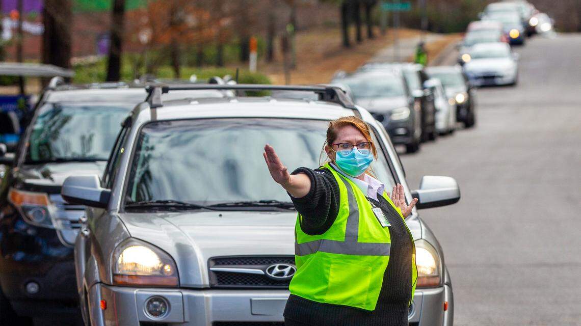 A worker directs traffic as vehicles line Kidd Road at a COVID-19 testing site in Raleigh Wednesday morning Dec. 22, 2021. Waits of more than 40 minutes long were reported at the site during morning hours.