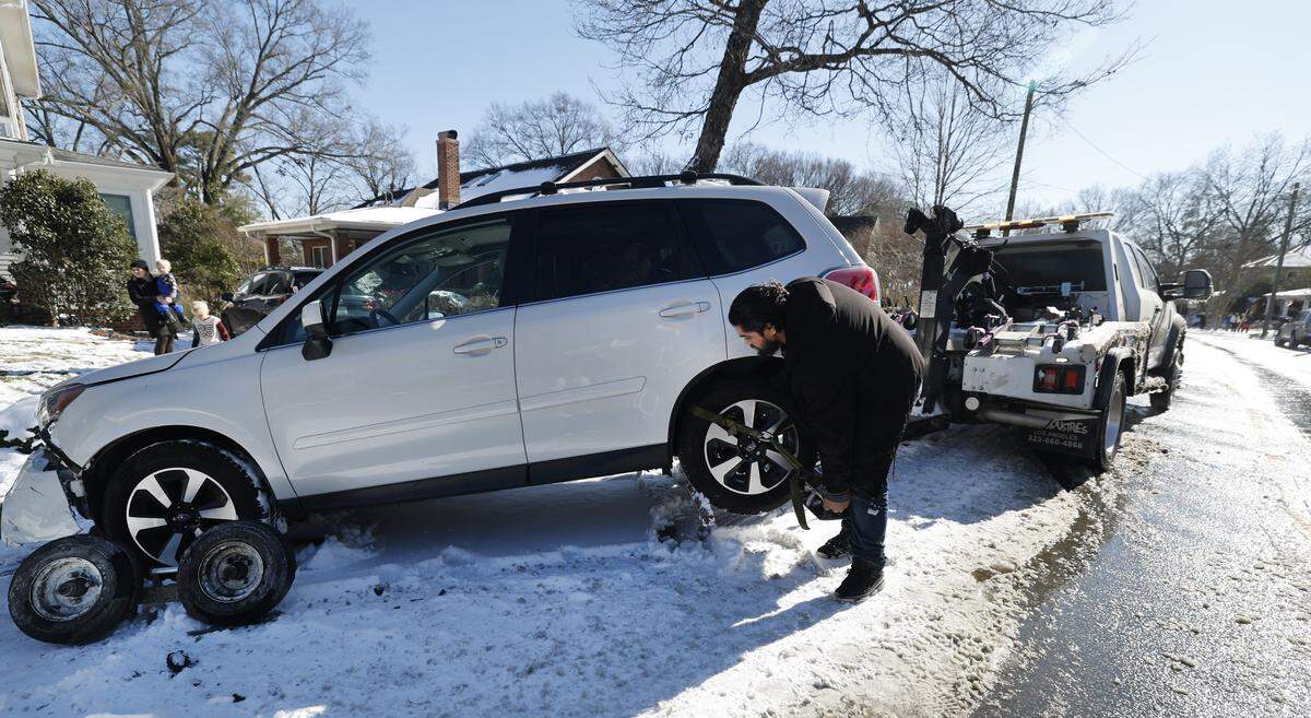 Carlos Martinez with Deliberate Fast Towing in Zebulon hooks up a vehicle Sunday, Feb. 1, 2026. The Subaru was hit overnight on a snowy street. Martinez said he started his shift at 5 a.m. and he has been going to call after call all day.
