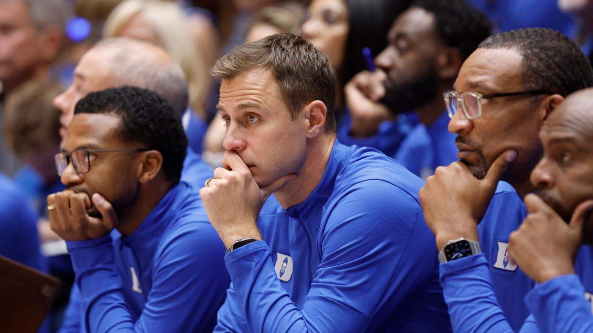 Duke head coach Jon Scheyer watches during the second half of Duke’s 80-62 victory over Southern Indiana at Cameron Indoor Stadium in Durham, N.C., Friday, Nov. 24, 2023. Associate head coaches Jai Lucas, left, and Chris Carrawell sit next to Scheyer. On the right is assistant coach Emanuel Dildy.