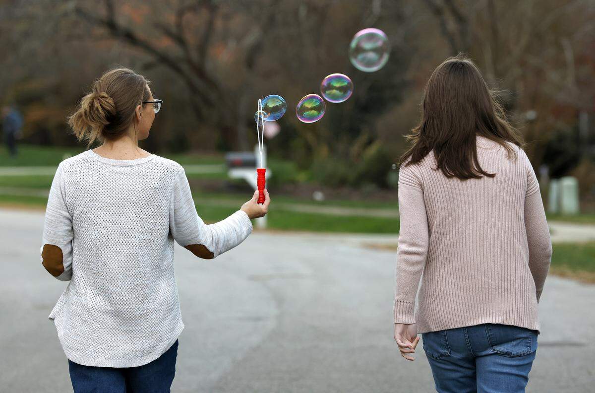 Krista Caraway blows bubbles as she walks with Lexi Abernethy in their Carrboro neighborhood.