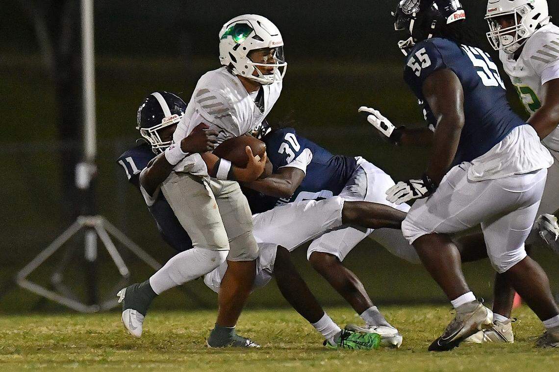 Cardinal Gibbons quarterback Gannon Jones (3) is sacked by Southeast Raleigh's Keysaun Eleazer (11) and Jaquan Higgins (30) during the first half. The Southeast Raleigh Bulldogs and the Cardinal Gibbons Crusaders met in a non-conference football game in Raleigh, N.C. September 12, 2025