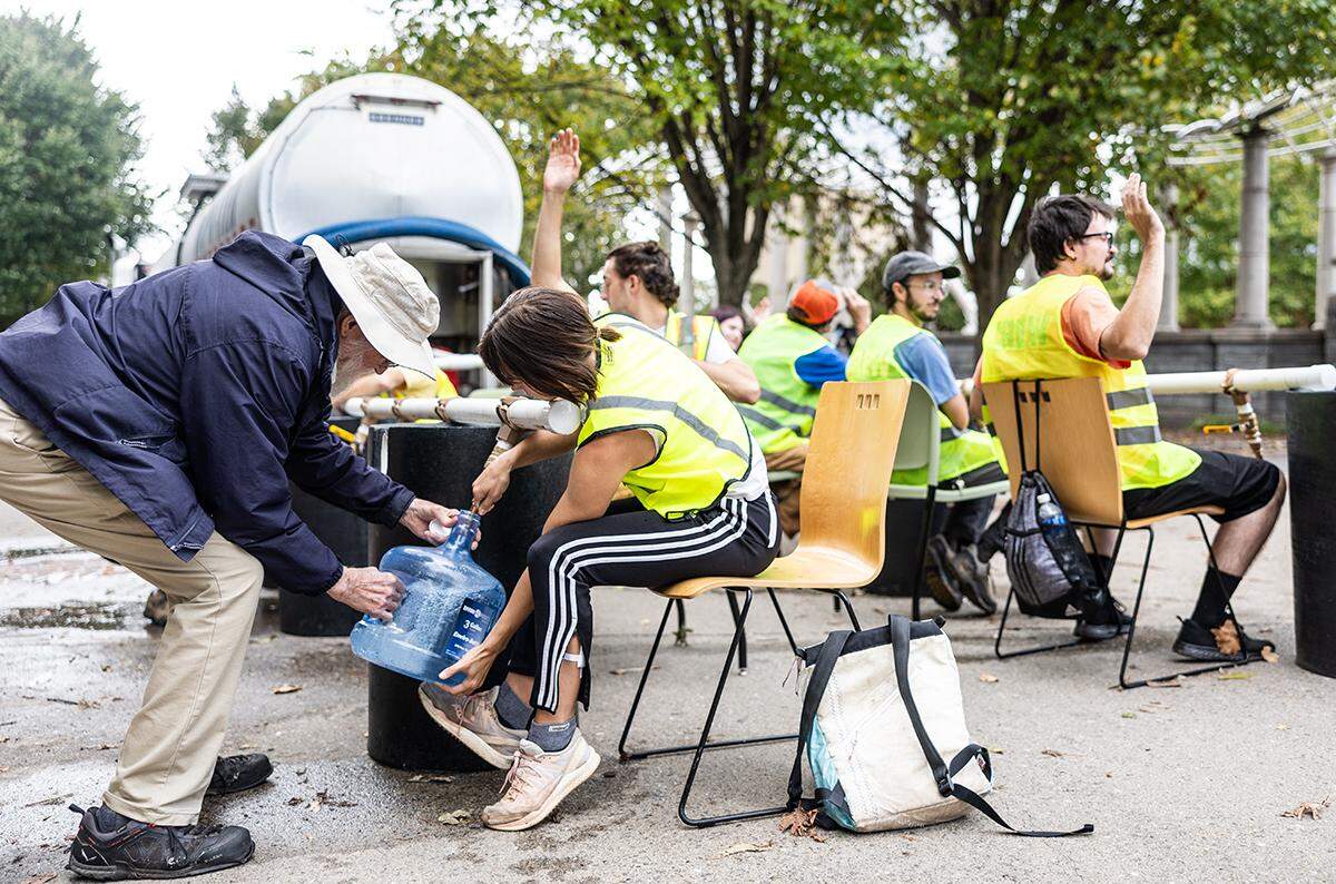 Volunteers fill containers of water for the community at a water distribution site at Pack Square in Asheville, N.C. on Tuesday, October 1, 2024.