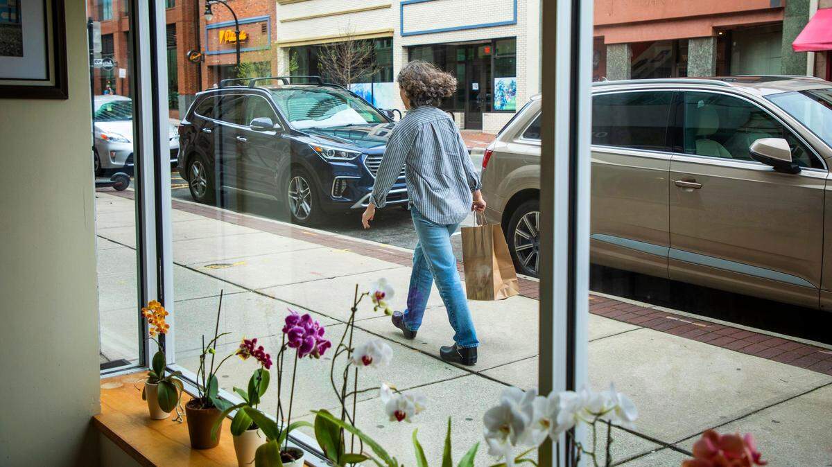 Sarah Bell walks away with her to-go order from Copa, as the restaurant practices and trains its staff on the workflow of filling an increasing number of to-go orders and offering curbside service, in response to preventing the spread of COVID-19, on Friday, March 13, 2020, in Durham, N.C.