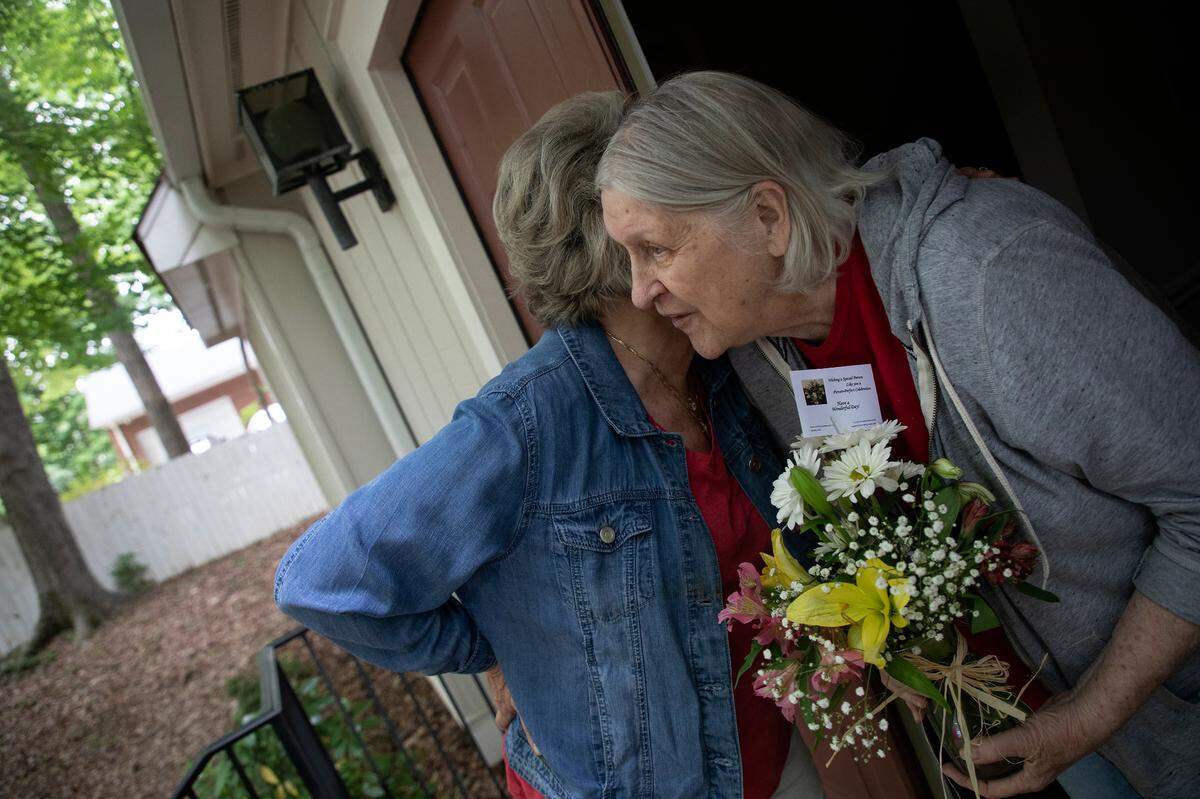 Marie Martin gets a hug from Beckie Mitchem after delivering a Mother’s Day flower arrangement on Friday, May 6, 2022, in Cary, N.C.