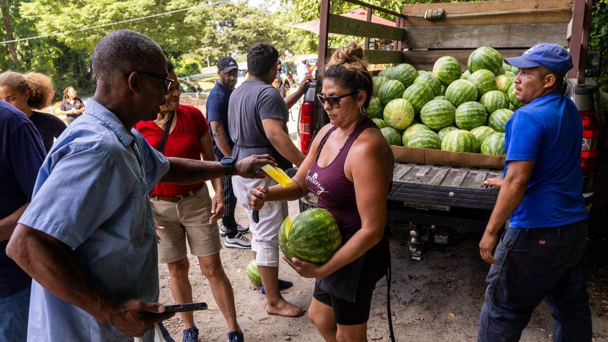 “The Watermelon Lady,” Sanjuana Sanchez, offers samples of fresh yellow watermelon from the back of a pickup truck on New Bern Avenue in Raleigh on Thursday, June 20, 2024. Sanchez saw an uptick in watermelon and fresh fruit sales Thursday as the Triangle experienced a heat wave.