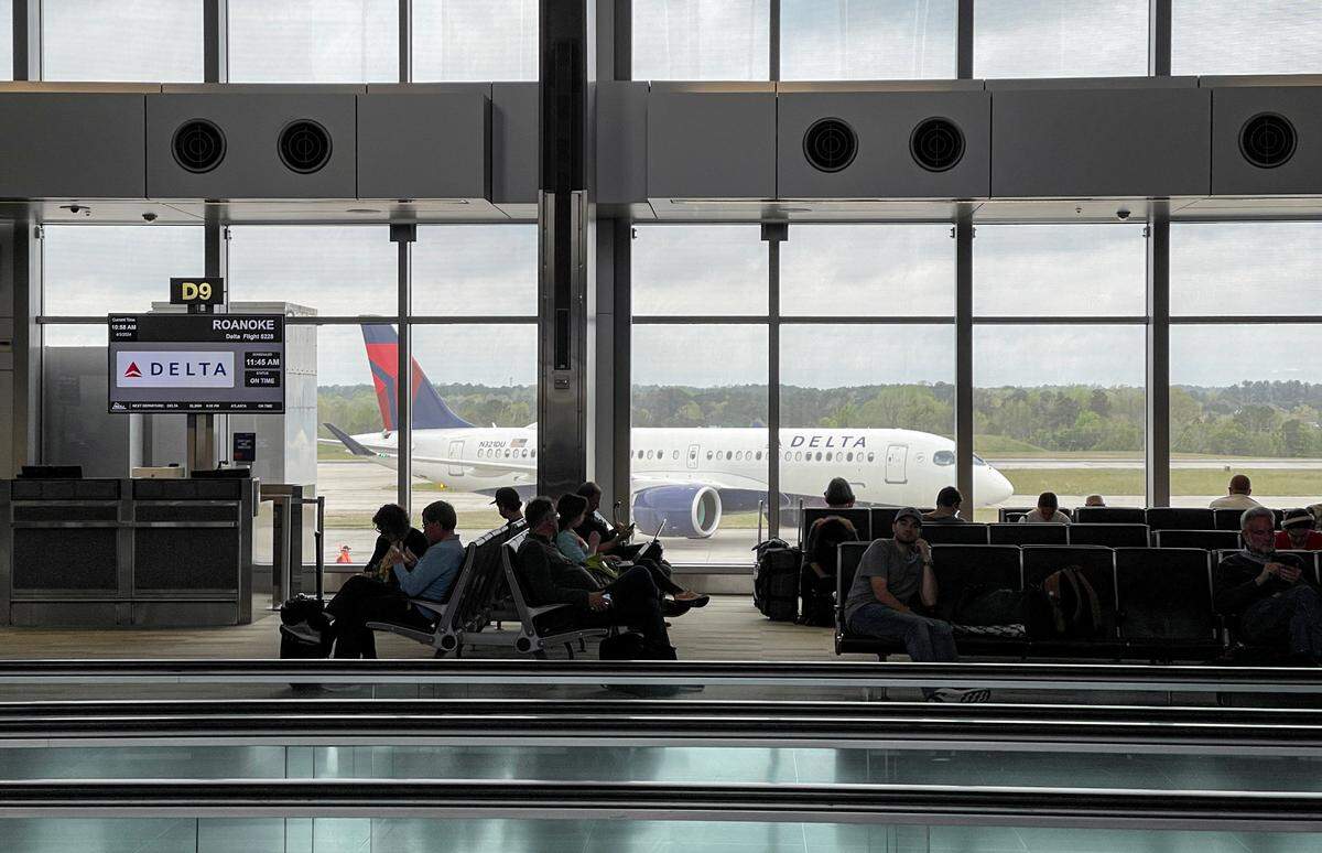 As a Delta plane passes by passengers wait for flights in Terminal 2 of Raleigh-Durham International Airport on April 3, 2024.