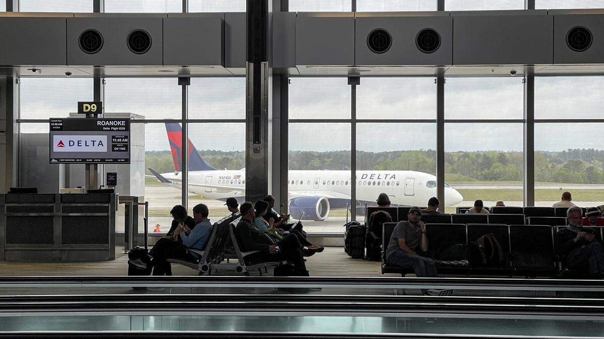 Passengers wait for flights in Terminal 2 of Raleigh-Durham International Airport on April 3, 2024, as a Delta plane passes by.