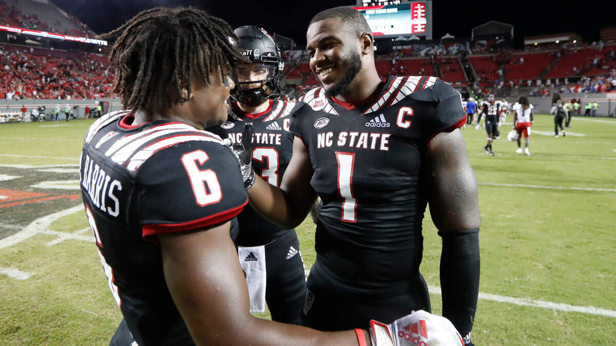 N.C. State quarterback Devin Leary (13) and linebacker Isaiah Moore (1) celebrate with safety Jakeen Harris (6) after N.C. State’s 34-27 victory over Louisiana Tech at Carter-Finley Stadium in Raleigh, N.C., Saturday, October 2, 2021.