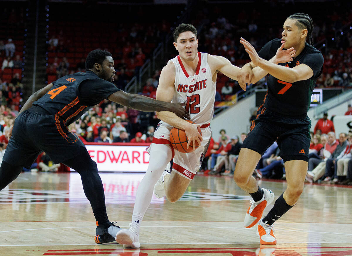 N.C. State’s Michael O’Connell drives to the basket past Miami’s Bensley Joseph and Kyshawn George during the first half of the Wolfpack’s game on Tuesday, Jan. 30, 2024, at PNC Arena in Raleigh, N.C.