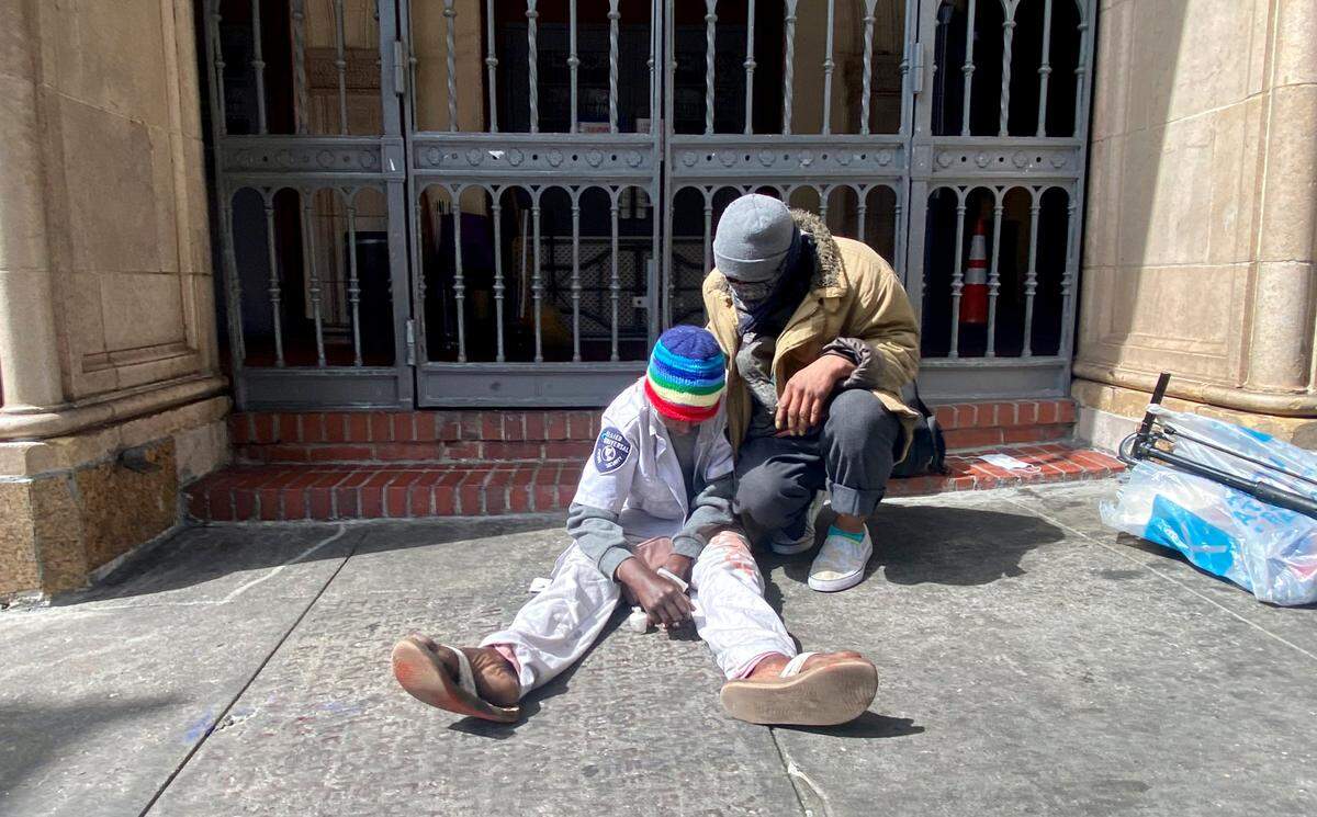 An older man comforts a younger one on Wednesday along Taylor St. in San Francisco, near a community outreach center and church. Similar scenes are common throughout the Tenderloin, an area known for its large homeless population.