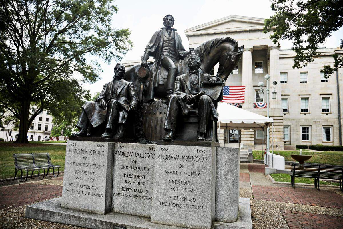 Presidents North Carolina Gave the Nation monument shows the three U.S. presidents from North Carolina. Andrew Jackson is riding a horse, with James K. Polk seated in front on him on the left and Andrew Johnson seated in front of him on the right. Two cannons flank a brick sidewalk leading out to the street.