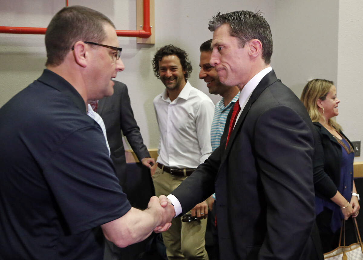The Canes’ Justin Williams, center, looks on as a well-wisher congratulates Rod Brind’Amour, right, after Brind’Amour was named the new head coach of the Carolina Hurricanes NHL team during a press conference at PNC Arena in Raleigh, NC on May 9, 2018. Majority owner Tom Dundon also announced that Don Waddell would be the team’s general manager, a position he has held in the interim since Ron Francis’s departure several weeks ago. Williams and Brind’Amour were teammates on the ice when the team won the Stanley Cup in 2006.