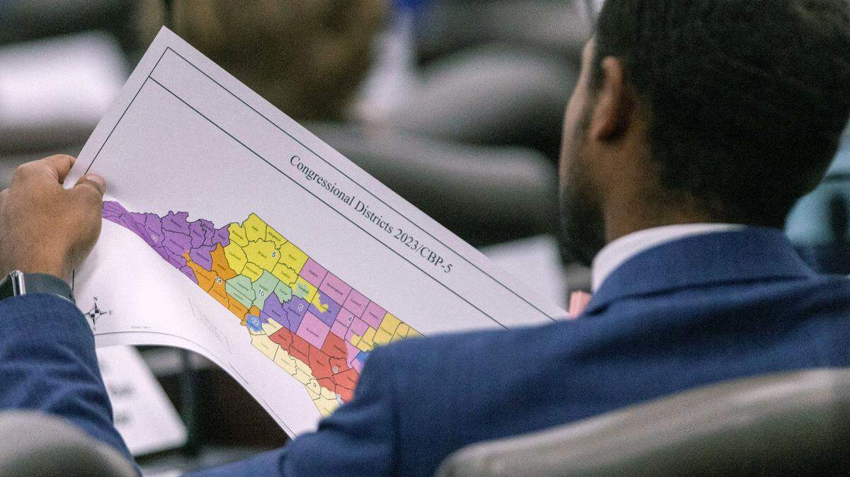 A North Carolina Senate staffer looks over a proposed congressional map during a Senate Committee on Redistricting and Elections meeting at the Legislative Office Building in Raleigh, Thursday, October. 19, 2023.