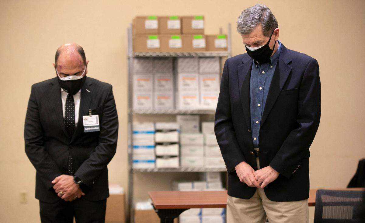 Donald Gintzig, WakeMed President & CEO, and North Carolina Governor Roy Cooper observe a moment of silence on the one year anniversary of the first diagnosed case of COVID-19 in North Carolina on Wednesday, March 3, 2021 at WakeMed in Raleigh, N.C. Moments later Governor Cooper received his COVID-19 vaccination.