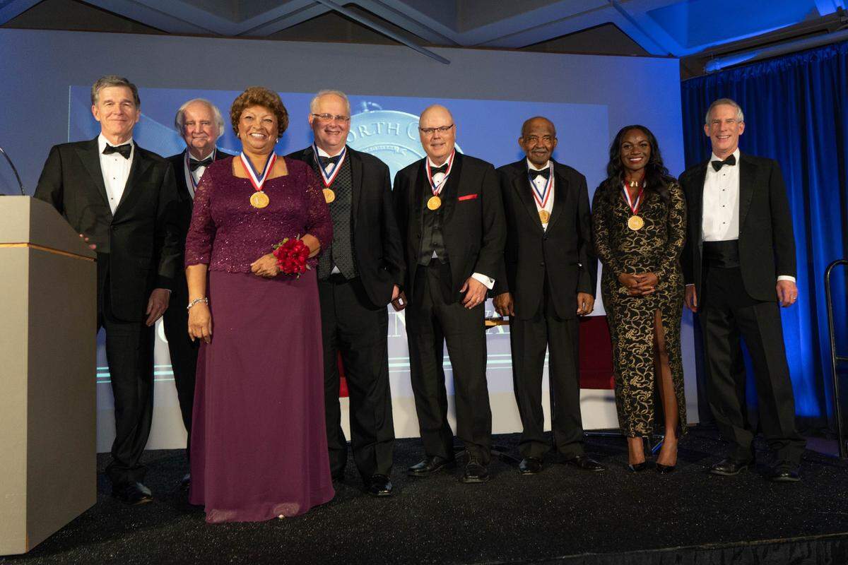 Nine North Carolinians were presented the North Carolina Award, the state’s highest honor, by Governor Roy Cooper at a Nov. 18, 2021, ceremony at the North Carolina Museum of Art. From left: Gov. Roy Cooper, Blake Wilson, Maria Spaulding, Ralph Baric, David Holt, Dudley Flood, Kizzmekia Corbett, and DNCR Secretary Reid Wilson. Not pictured: Francis Collins, Tim Tyson and André Leon Talley.
