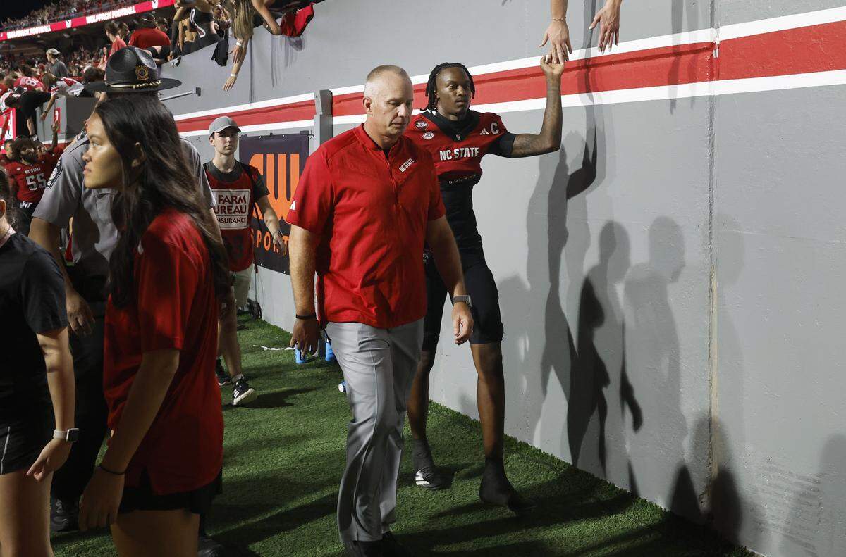 N.C. State head coach Dave Doeren walks off the field after Virginia Tech’s 23-21 victory over N.C. State at Carter-Finley Stadium in Raleigh, N.C., Saturday, Sept. 27, 2025. N.C. State quarterback CJ Bailey (11) is to the right. 