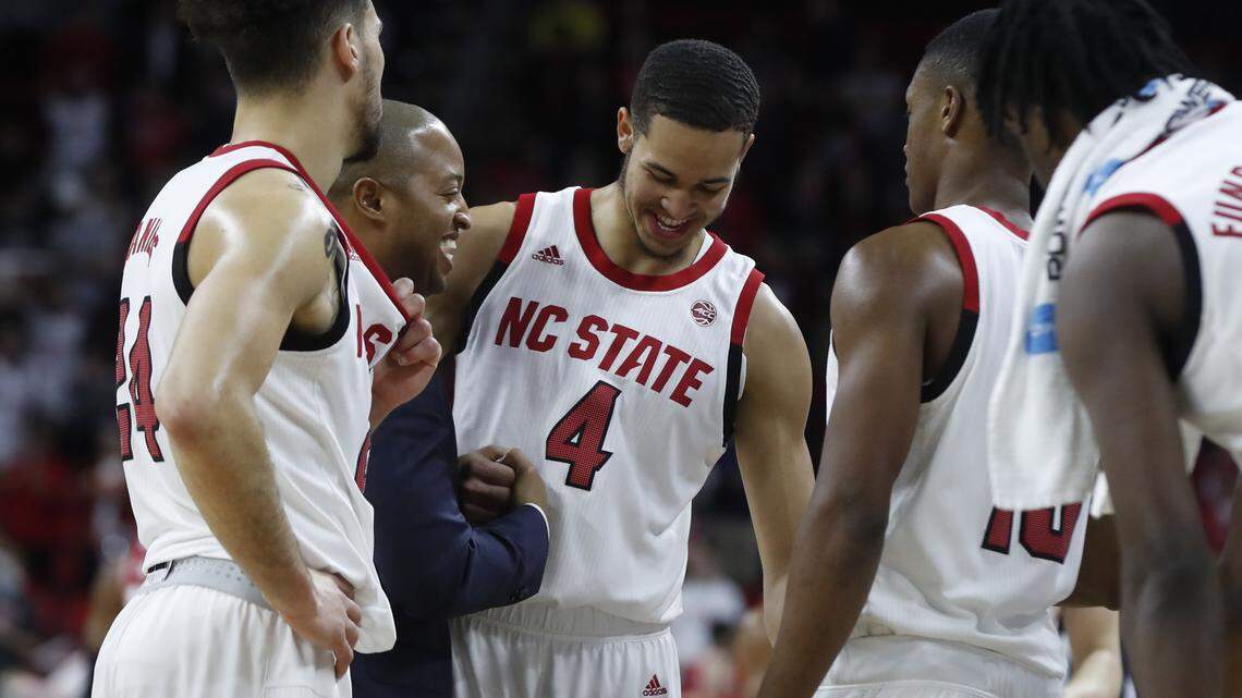 N.C. State assistant coach Takayo Siddle celebrates with Jericole Hellems (4) as time runs out during the second half of N.C. State’s 69-54 victory over Wisconsin at PNC Arena in Raleigh, N.C., Wednesday, Dec. 4, 2019.