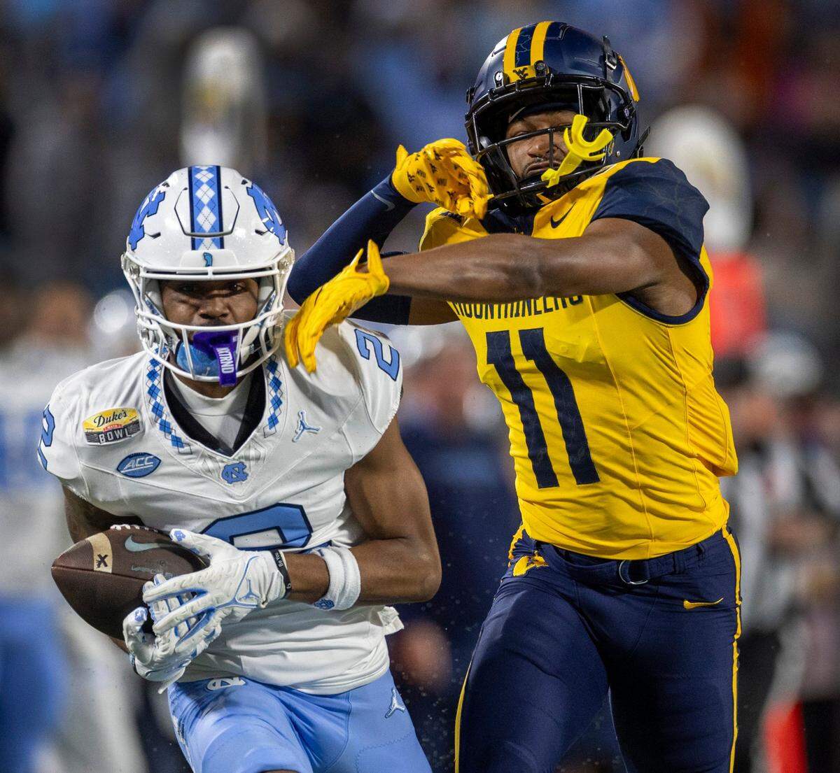 North Carolina’s Gavin Blackwell (2) picks up 47-yards on a pass completion from quarterback Conner Harrell in the first quarter against West Virginia’s Beanie Bishop Jr. (11) during the Duke’s Mayo Bowl on Wednesday, December 27, 2023 at Bank of American Stadium in Charlotte, N.C.