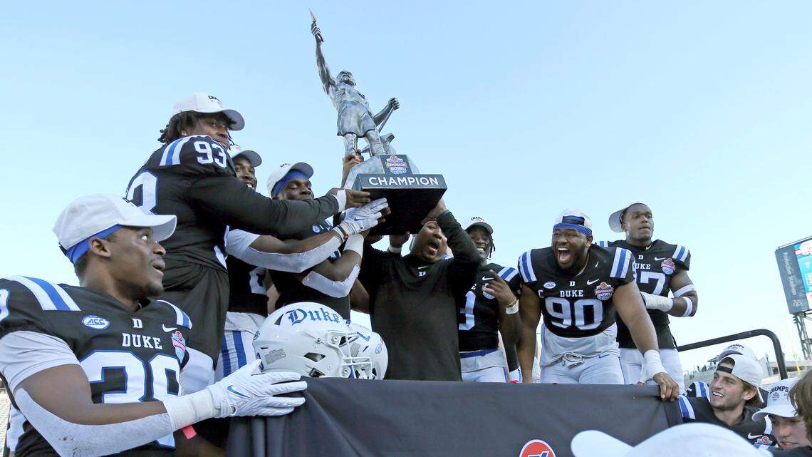 Duke Blue Devils players and interim head coach Trooper Taylor celebrate with the Birmingham Bowl trophy after defeating the Troy Trojans in Birmingham, Ala. Saturday, Dec. 23, 2023.