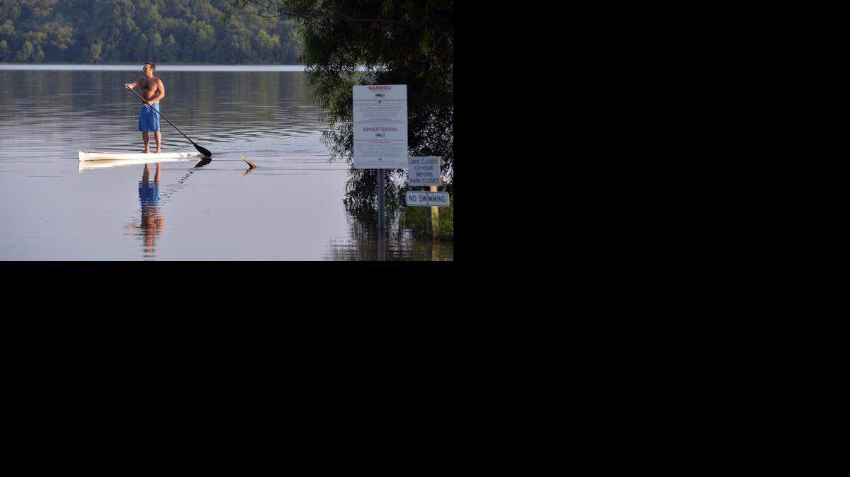 Rob Bailey of Holly Springs heads to shore at Lake Crabtree on his standing paddle board late Wednesday afternoon, July 17, 2014. A large sign at right warns people not to take fish from the lake due to contamination from PCBs. Lake Crabtree is downstream from $82 million Superfund cleanup at the site of the Triangle’s nastiest industrial polluter, Ward Transformer Co. Ward’s half-century legacy of toxic PCB contamination will linger in the Raleigh area for many years to come, in creeks and lakes from Raleigh-Durham International Airport west of the city to the Neuse River on the east side.
