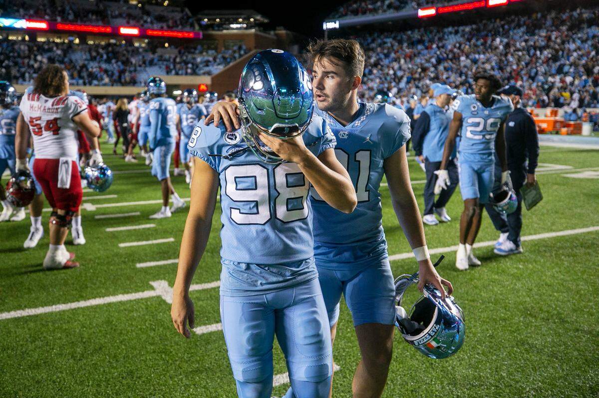 North Carolina punter Ben Kiernan (91) consoles kicker Noah Burnette (98) after Burnette missed a 35-yard field goal attempt in overtime to give N.C. State a 30-27 victory on Friday, November 25, 2022 at Kenan Stadium in Chapel Hill, N.C.