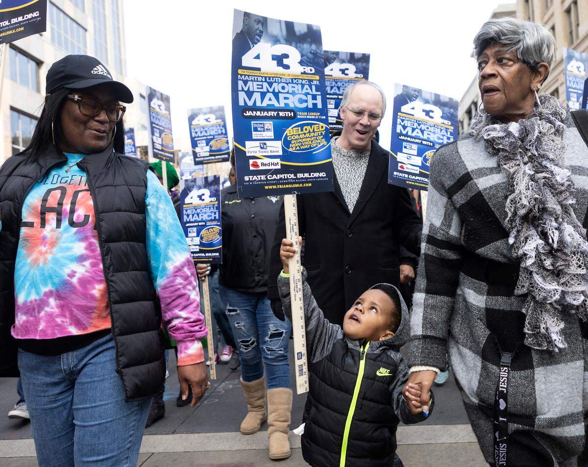 Diyan Williams, 3, holds a sign aloft while walking with Lady Trecinda Payne during the Martin Luther King, Jr. Memorial March on Monday, Jan. 16, 2023, in Raleigh, N.C.