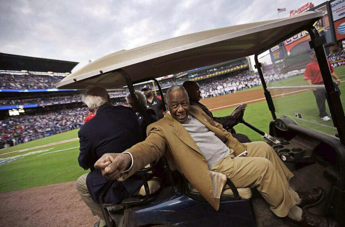 Hank Aaron gestures to the crowd as he leaves the field following a ceremony celebrating the 40th anniversary of his 715th home run before the start of a baseball game between the Atlanta Braves and the New York Mets, Tuesday, April 8, 2014, in Atlanta.