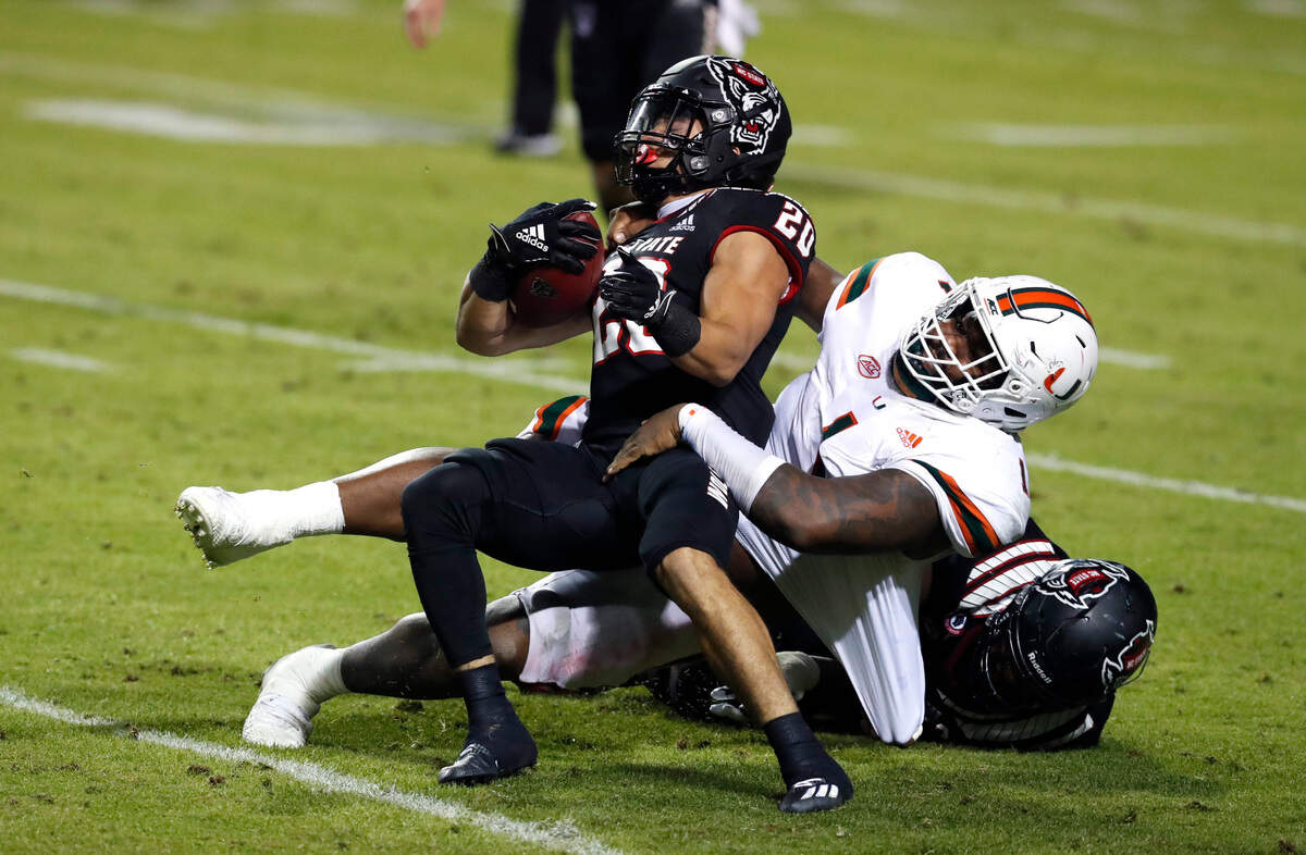 Miami defensive lineman Nesta Jade Silvera (1) tackles N.C. State running back Jordan Houston (20) during the second half of Miami’s 44-41 victory over N.C. State at Carter-Finley Stadium in Raleigh, N.C., Friday, Nov. 6, 2020.