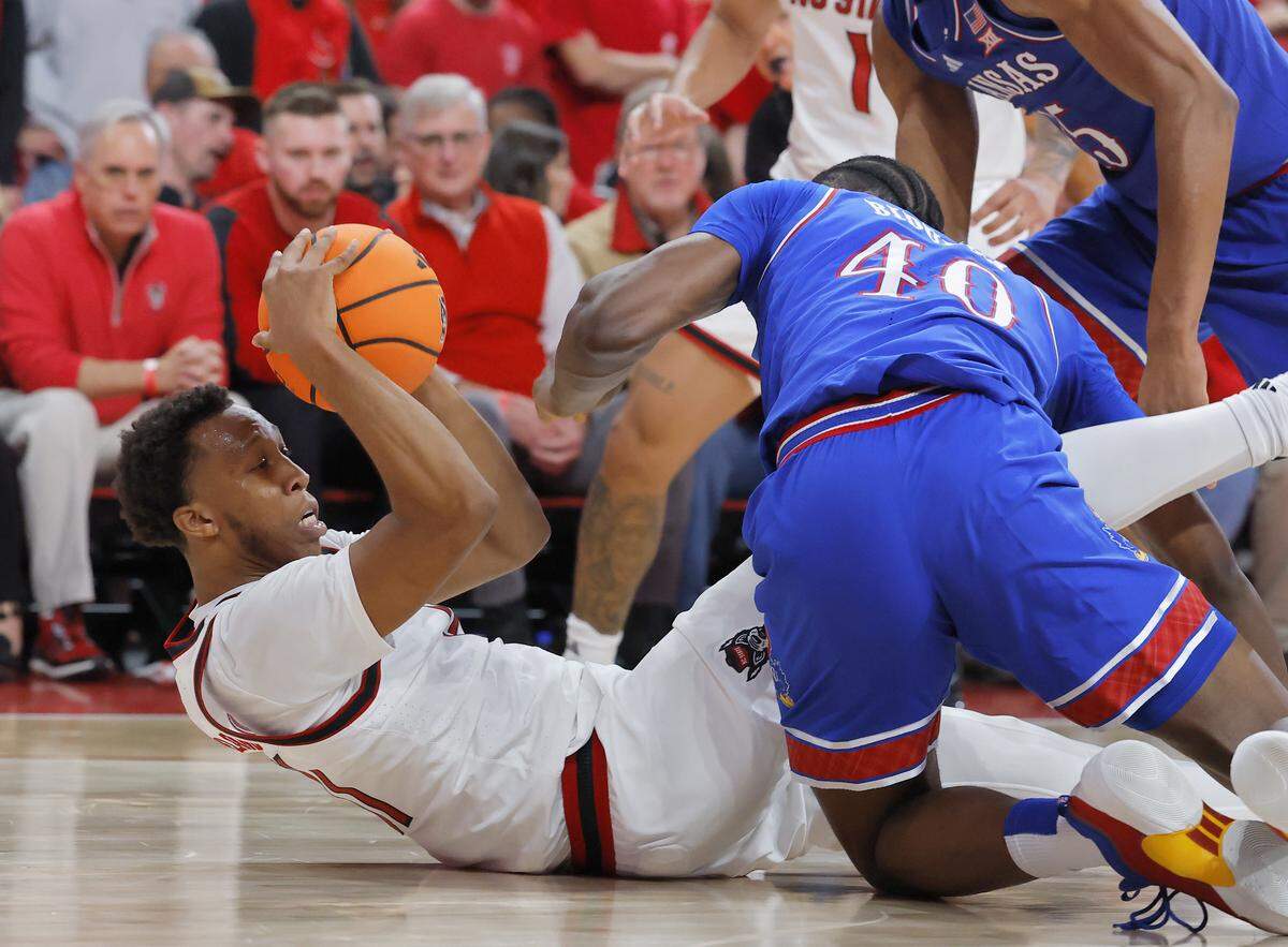 N.C. State’s Quadir Copeland looks to pass around Kansas’ Flory Bidunga during the second half of the Wolfpack’s 77-76 overtime loss on Saturday, Dec. 13, 2025, at Lenovo Center in Raleigh, N.C.