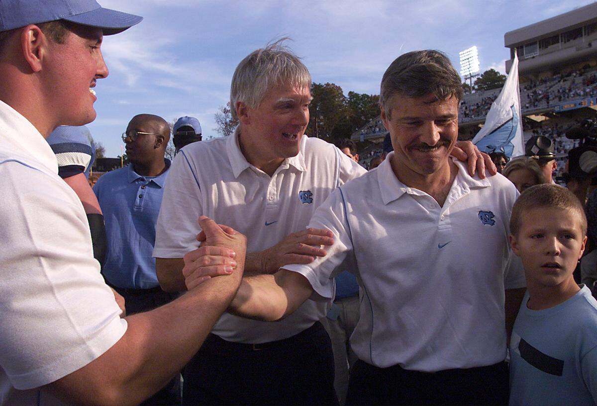 UNC’s Carl Torbush leaves Kenan Stadium with his son Trey as he’s congratulated by assistant coach Kenny Browning after a Tar Heel win in 1999.