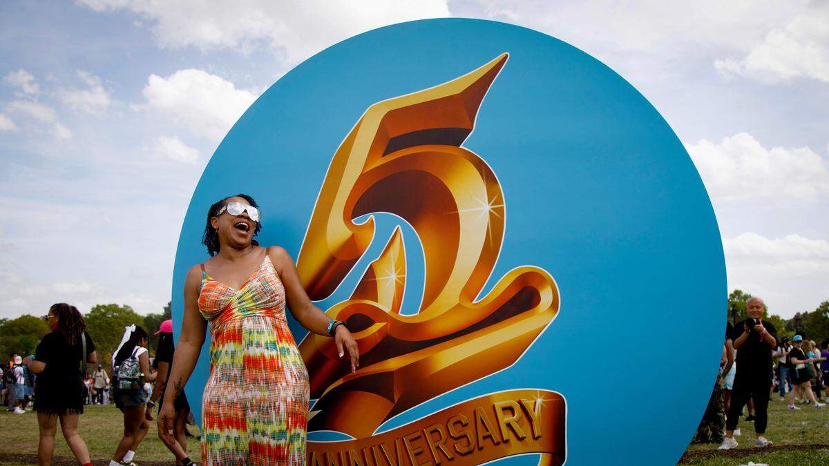 Angeliyah Owens laughs while posing for a portrait with artwork at the fifth Dreamville Festival on Saturday, April 5, 2025, at Dorothea Dix Park in Raleigh, N.C.