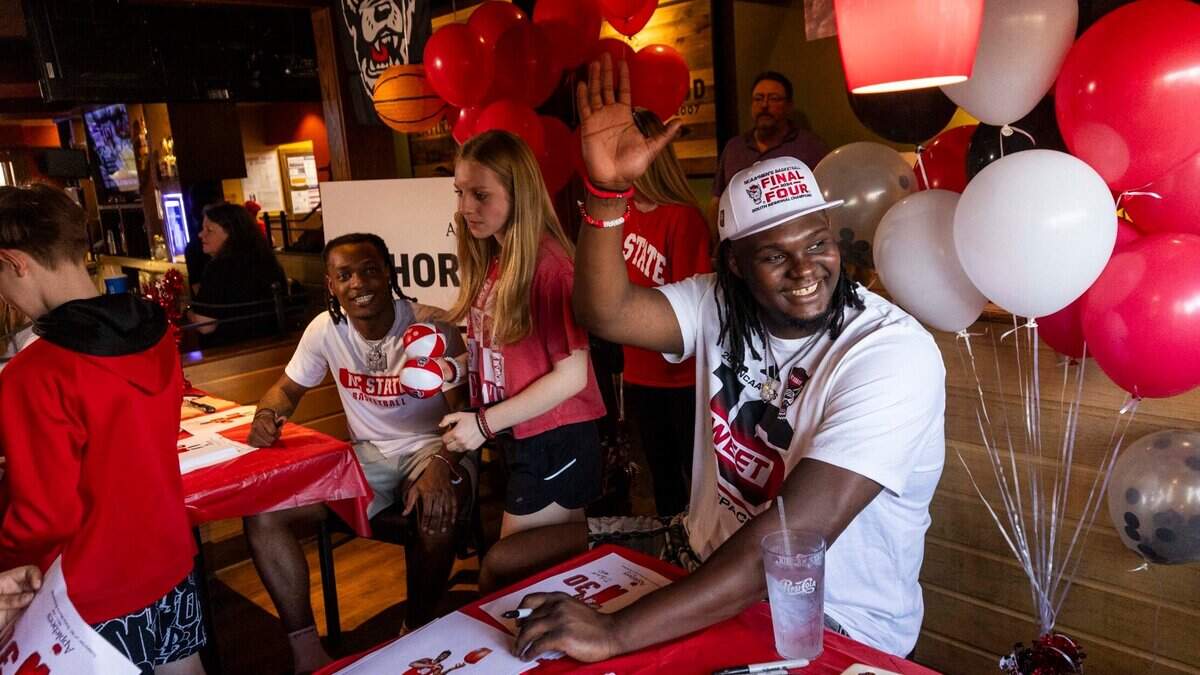 NC State’s DJ Burns Jr. waves to fans outside a window as Burns and DJ Horne, sign hundreds of autographs at Triangle Town Center Applebee’s in Raleigh on Tuesday, April 2, 2024 ahead of the Wolfpack’s Final Four game on Saturday.