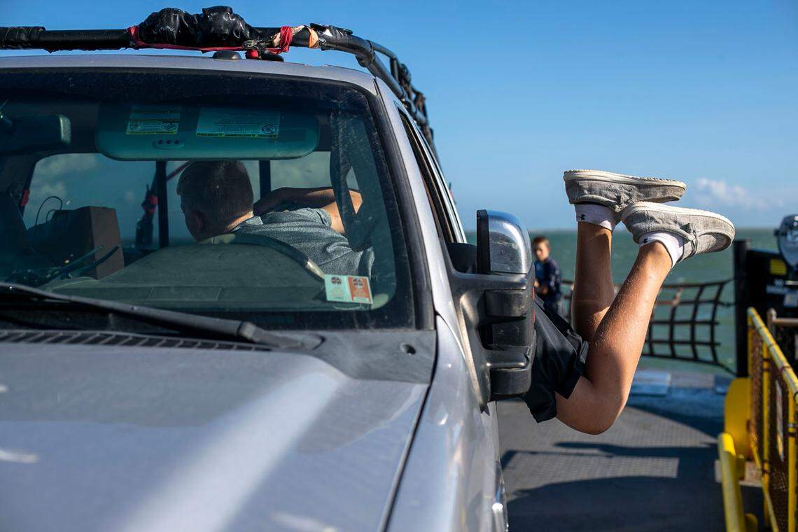 Patrick Hardesty, age 14, of Gilette, Wymoning, dives into the truck cab to grab some candy aboard the Cape Point Ferry from Hatteras to Ocracoke on Thursday, July 1, 2021.