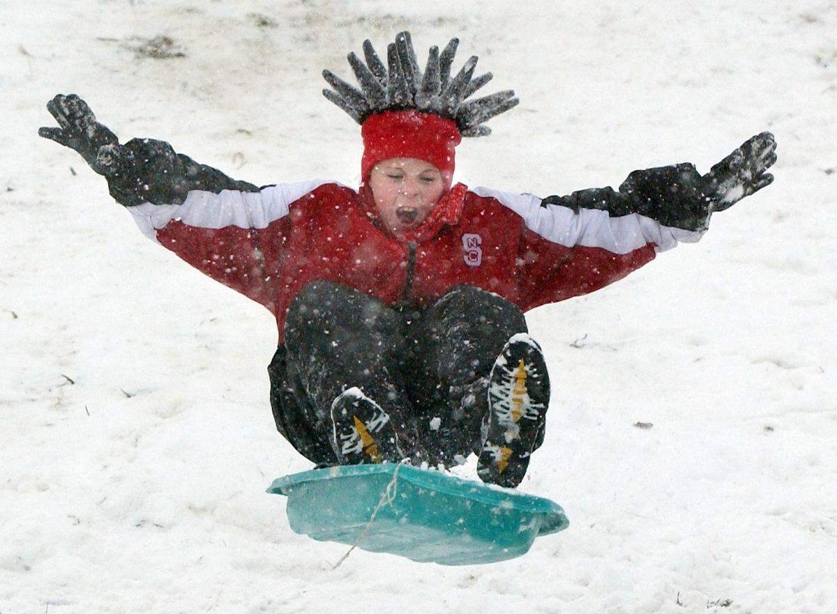 Chris Gass separates from his sled after going airborne over a jump while sledding down a hill at Bond Park in Cary in 2002.